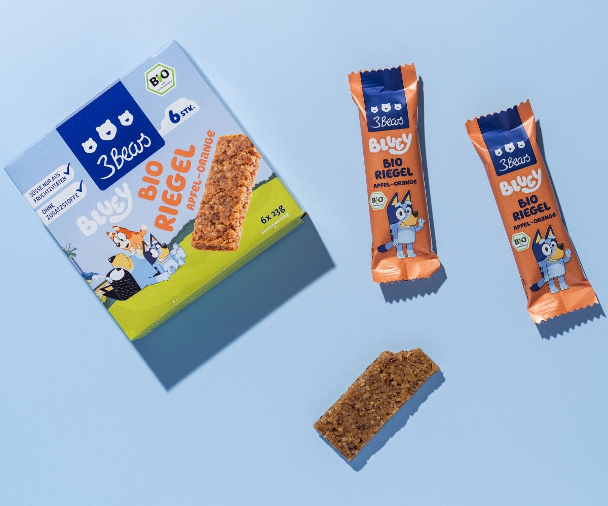 Ungeöffnete Bio Riegel Apfel-Orange neben einem Riegel ohne Verpackung