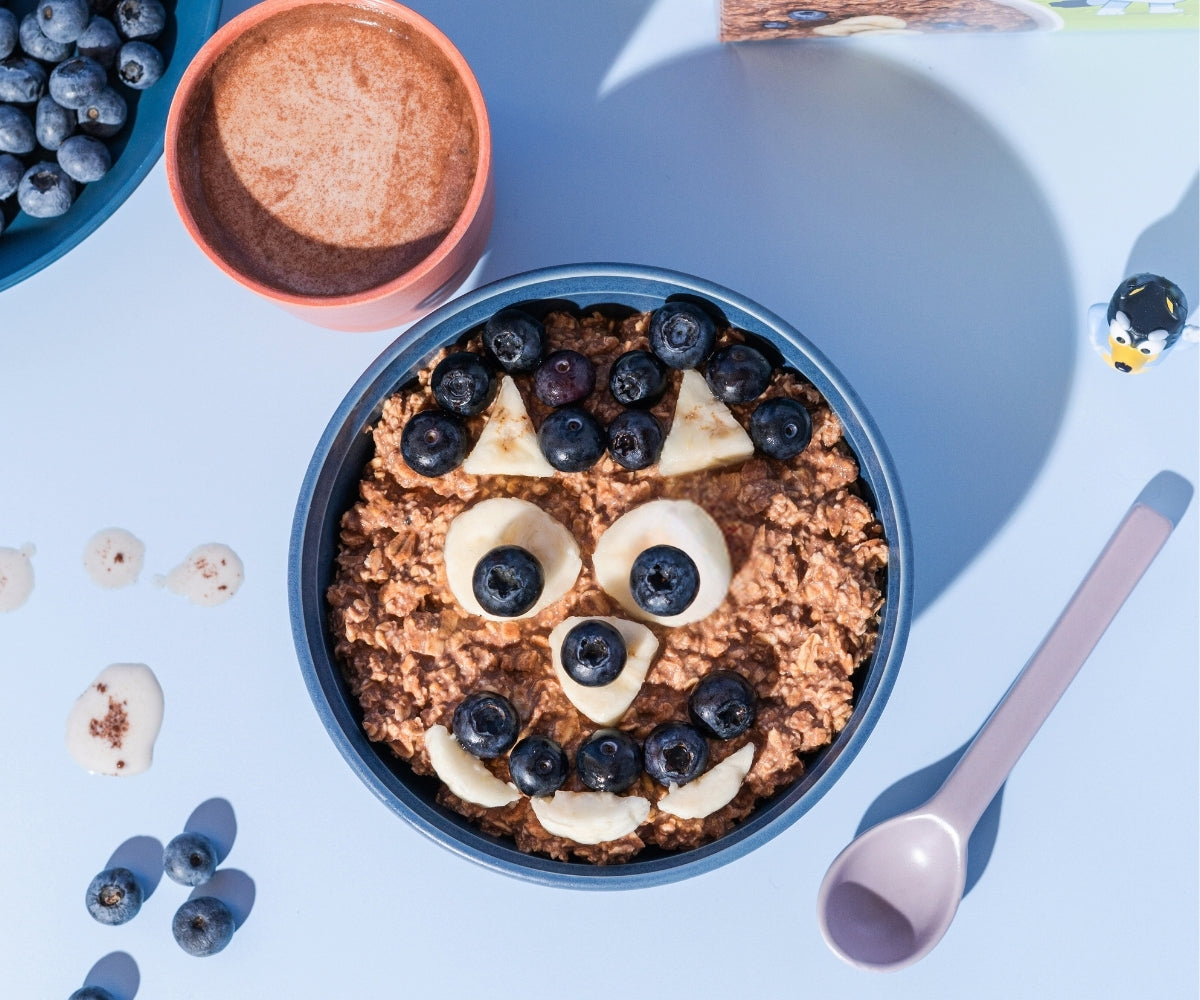 Organic cocoa-cinnamon porridge with milk in a bowl and fruit topping